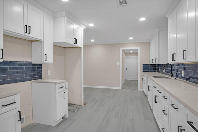 kitchen with white cabinetry, sink, decorative backsplash, and light wood-type flooring