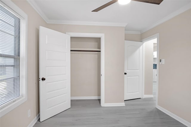 unfurnished bedroom with ornamental molding, ceiling fan, light wood-type flooring, and a closet