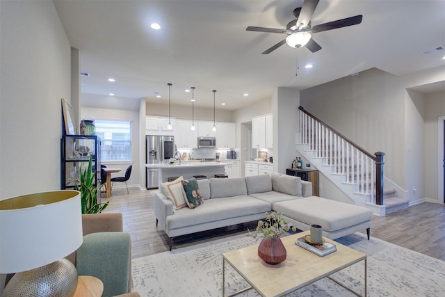 living room featuring sink, ceiling fan, and light hardwood / wood-style flooring