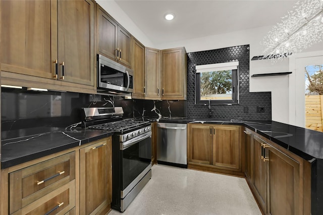 kitchen with appliances with stainless steel finishes, sink, dark stone countertops, and decorative backsplash