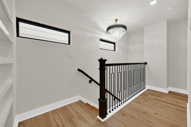 stairway with hardwood / wood-style floors and a notable chandelier