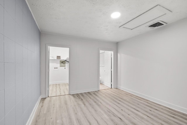 empty room featuring visible vents, baseboards, a textured ceiling, and wood finished floors