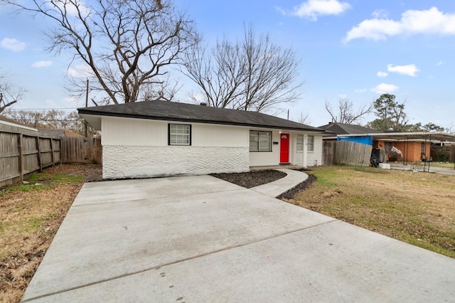 view of front of property featuring a front lawn, fence, and brick siding