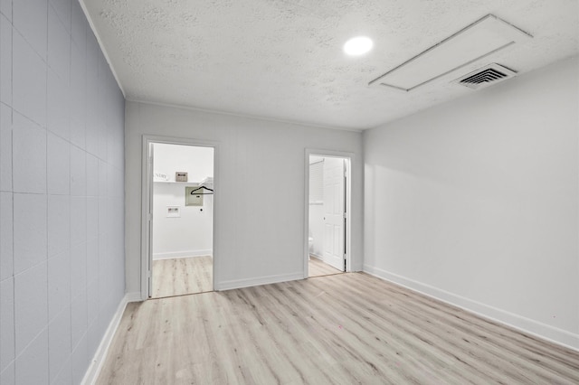 unfurnished room featuring baseboards, wood finished floors, visible vents, and a textured ceiling