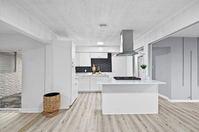 kitchen with visible vents, light wood finished floors, island range hood, and black gas stovetop