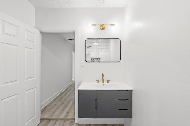 bathroom with vanity, wood finished floors, baseboards, and a textured ceiling