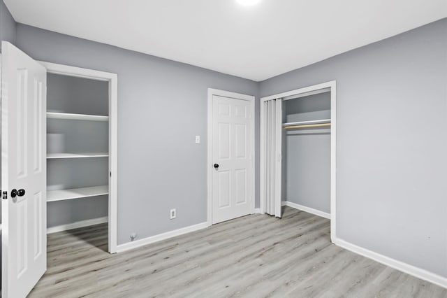 unfurnished bedroom featuring a closet, baseboards, and wood finished floors