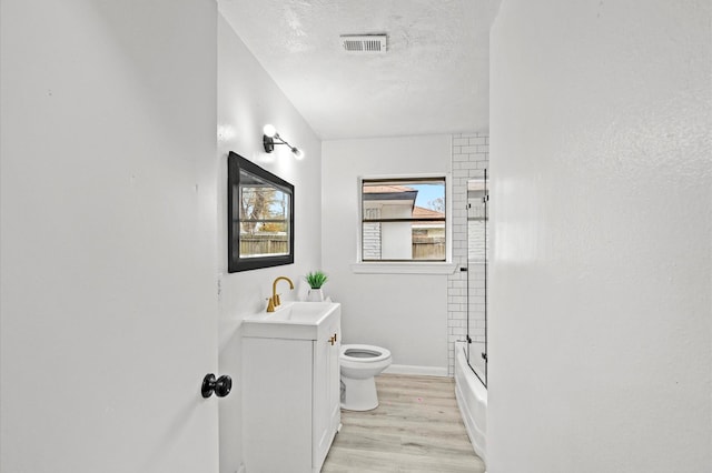 full bath with visible vents, toilet, a textured ceiling, wood finished floors, and vanity