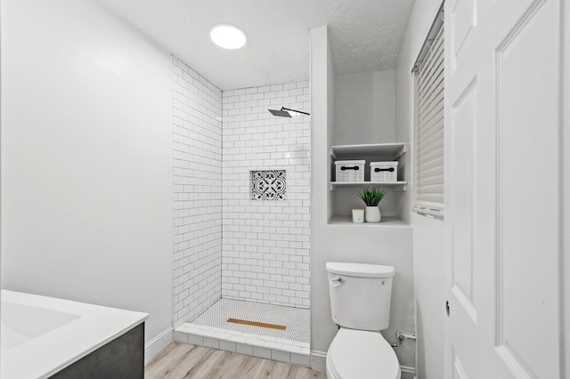 full bathroom featuring toilet, wood finished floors, a stall shower, and a textured ceiling