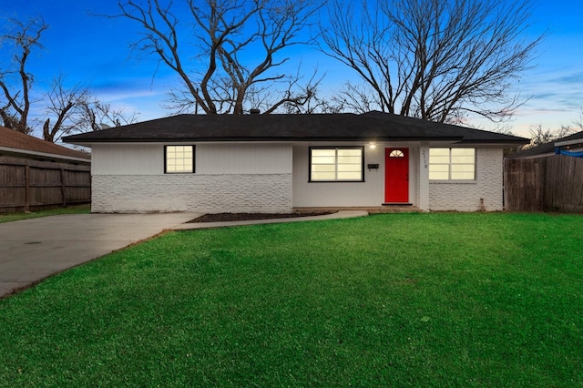 ranch-style home featuring a yard, fence, and brick siding