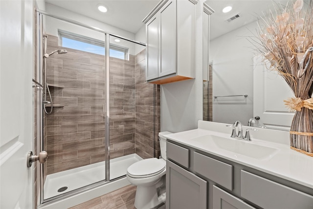 bathroom featuring a shower with door, vanity, hardwood / wood-style flooring, and toilet