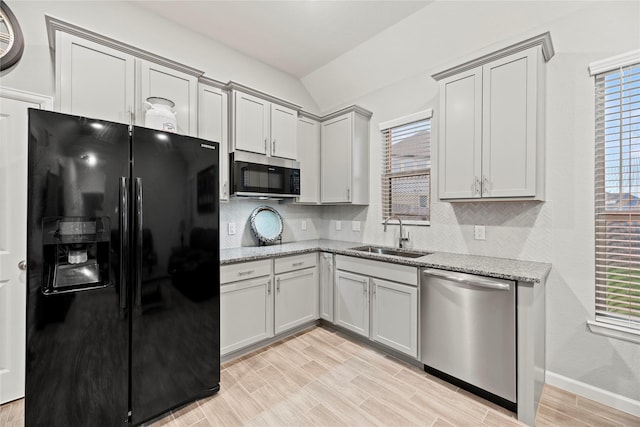 kitchen featuring sink, light stone counters, light hardwood / wood-style flooring, stainless steel appliances, and backsplash