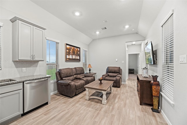 living room featuring lofted ceiling, sink, and light hardwood / wood-style flooring