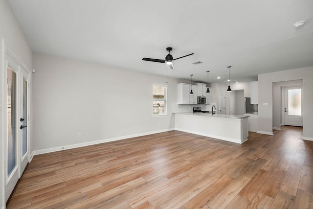 unfurnished living room with ceiling fan, plenty of natural light, and light hardwood / wood-style floors