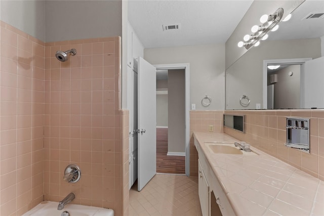 bathroom with tiled shower / bath, vanity, tile patterned floors, and a textured ceiling