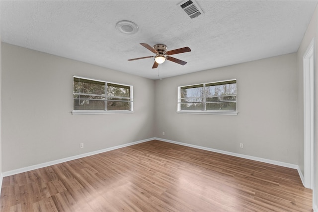 spare room with ceiling fan, a healthy amount of sunlight, a textured ceiling, and light wood-type flooring