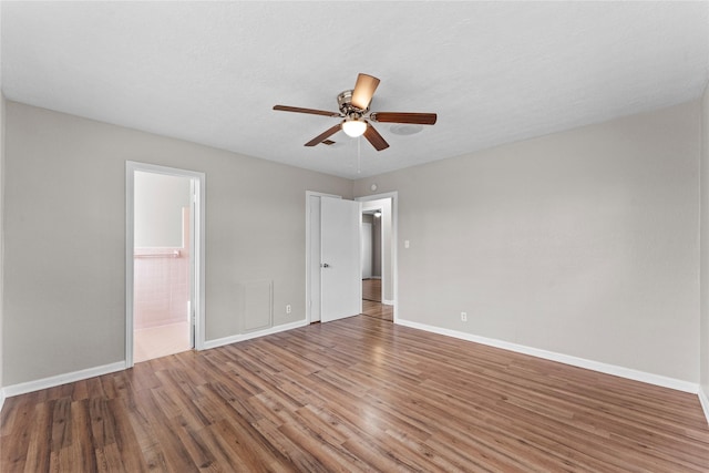 unfurnished bedroom with hardwood / wood-style flooring, ensuite bath, a textured ceiling, and ceiling fan