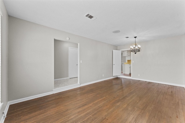 spare room with hardwood / wood-style floors and a notable chandelier