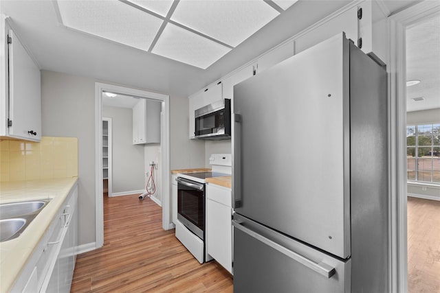 kitchen with white cabinetry, backsplash, light hardwood / wood-style flooring, and appliances with stainless steel finishes