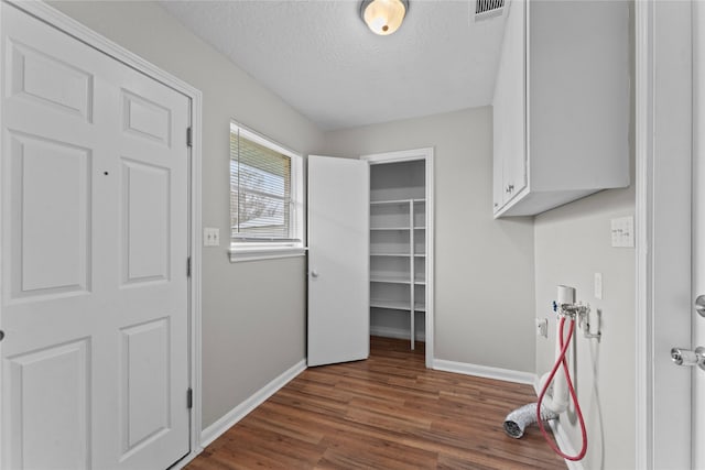 laundry room featuring washer hookup, dark wood-type flooring, cabinets, and a textured ceiling