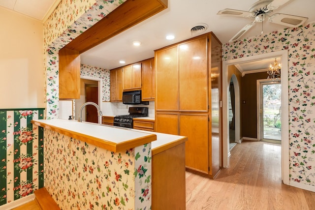 kitchen featuring ornamental molding, kitchen peninsula, sink, and black appliances