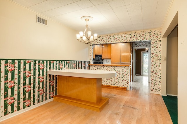 kitchen featuring ornamental molding, decorative light fixtures, light hardwood / wood-style floors, and kitchen peninsula