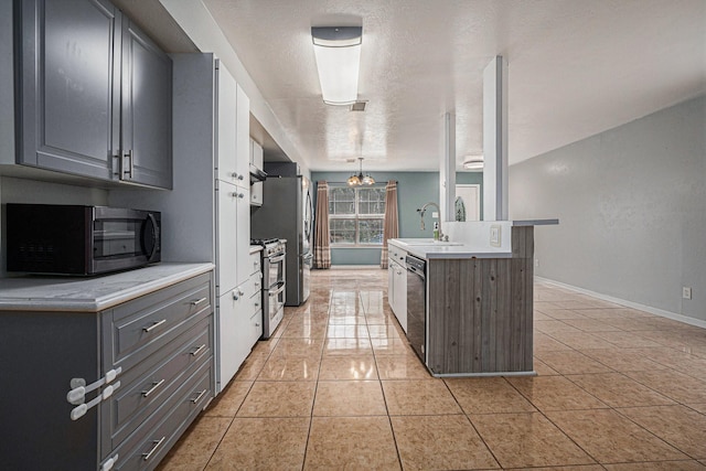 kitchen with light tile patterned flooring, appliances with stainless steel finishes, pendant lighting, sink, and a textured ceiling