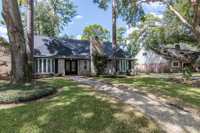 tudor home featuring a front yard and french doors