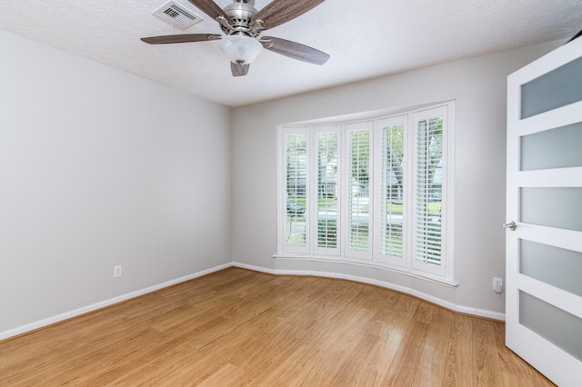 spare room featuring ceiling fan, light hardwood / wood-style floors, and a textured ceiling