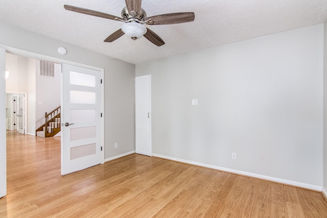 empty room featuring ceiling fan, a textured ceiling, and light wood-type flooring