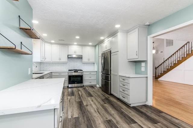 kitchen with sink, white cabinetry, stainless steel appliances, dark hardwood / wood-style floors, and light stone countertops