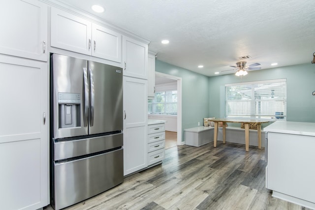 kitchen featuring white cabinetry, ceiling fan, light hardwood / wood-style floors, stainless steel refrigerator with ice dispenser, and a textured ceiling