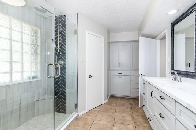 bathroom with tile patterned flooring, vanity, an enclosed shower, and a textured ceiling