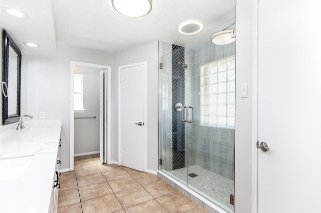 bathroom with vanity, a shower with door, tile patterned flooring, and a textured ceiling