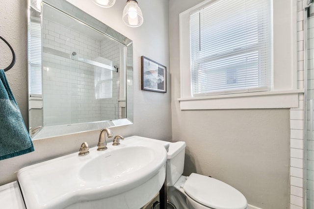 bathroom with a shower with shower door and toilet