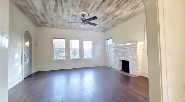 unfurnished living room featuring a brick fireplace, dark hardwood / wood-style floors, and ceiling fan