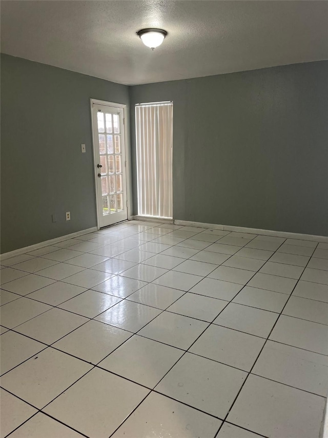 spare room featuring light tile patterned floors and a textured ceiling