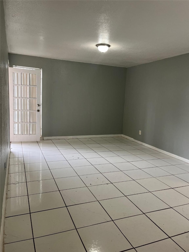 tiled empty room with a textured ceiling