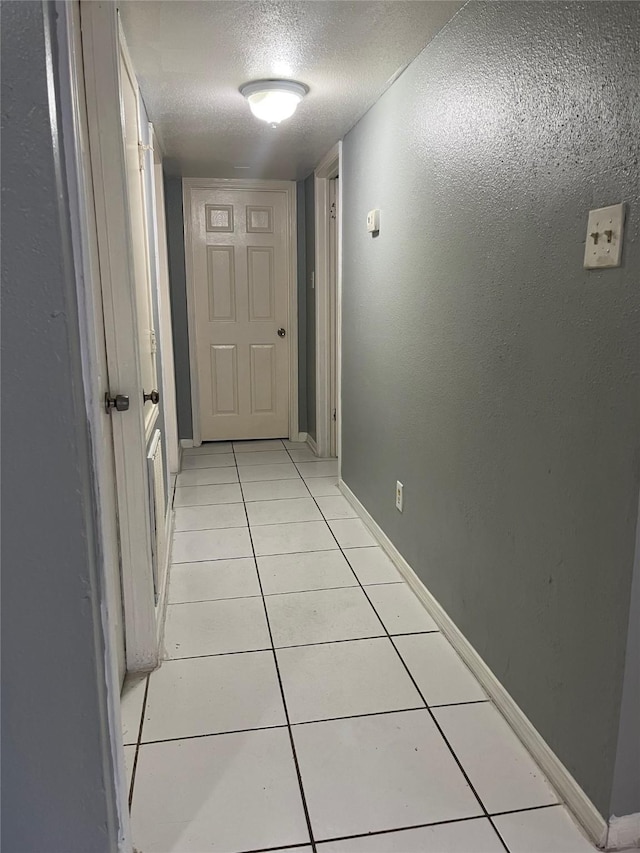 corridor with light tile patterned flooring and a textured ceiling