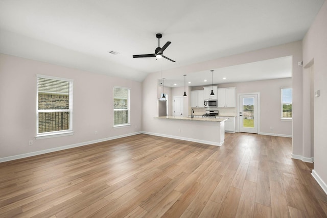 unfurnished living room featuring vaulted ceiling, sink, ceiling fan, and light wood-type flooring