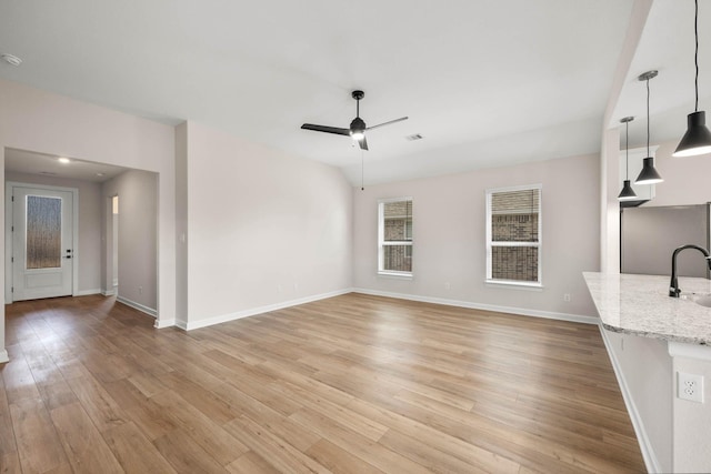 unfurnished living room featuring sink, ceiling fan, and light hardwood / wood-style flooring