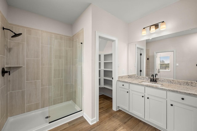 bathroom with tiled shower, vanity, and hardwood / wood-style floors