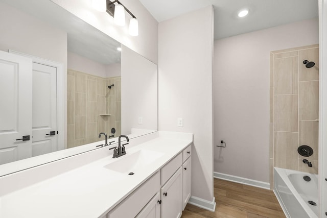 bathroom with vanity, hardwood / wood-style flooring, and tiled shower / bath