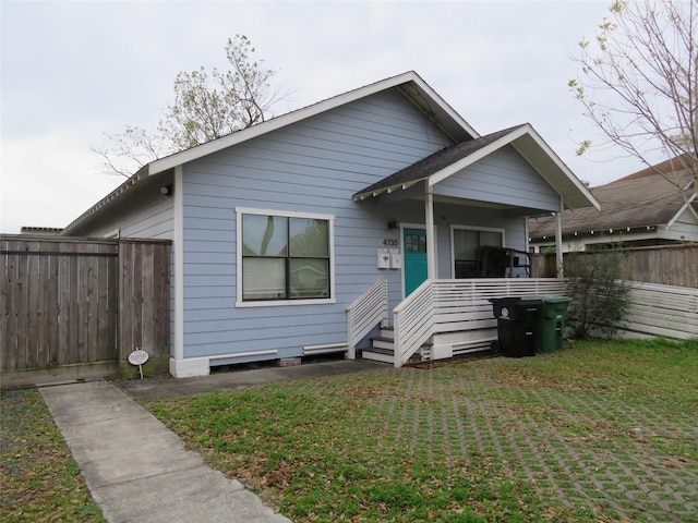 bungalow with covered porch and a front lawn