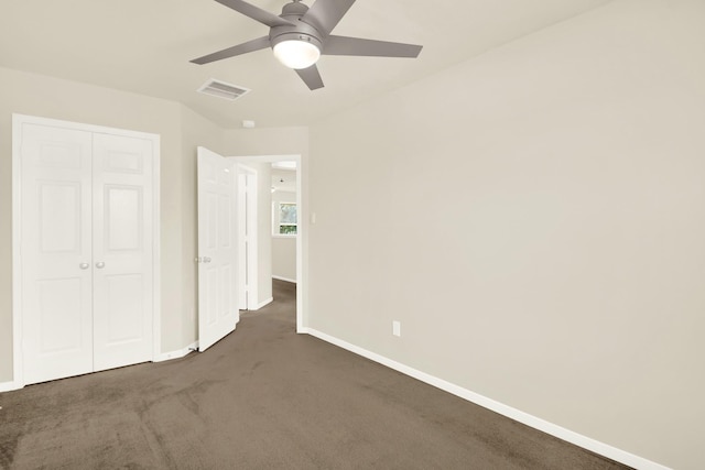 unfurnished bedroom with dark colored carpet, ceiling fan, and a closet