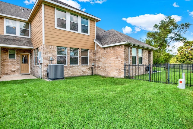 rear view of house with central AC and a lawn