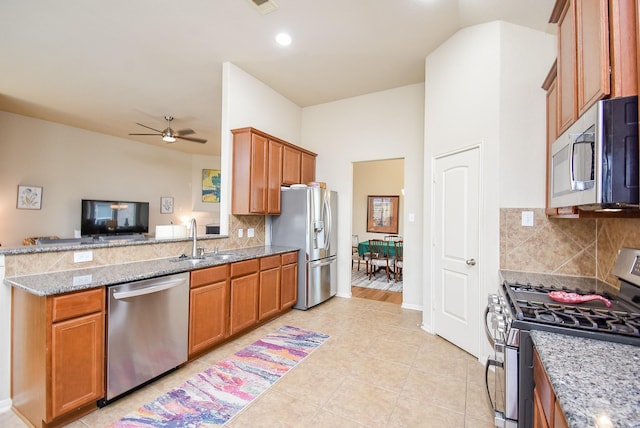 kitchen featuring sink, light tile patterned floors, ceiling fan, stainless steel appliances, and light stone countertops