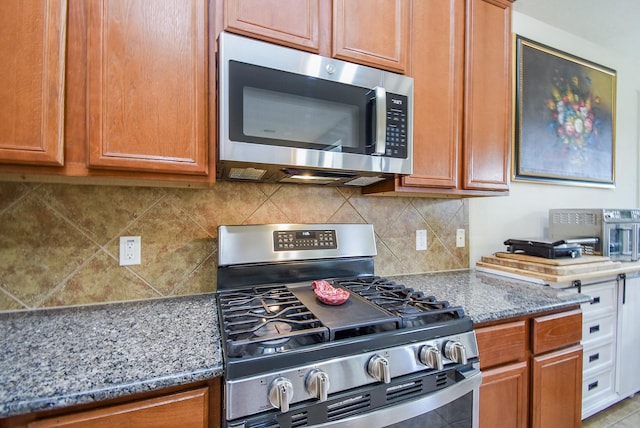 kitchen with light stone countertops, appliances with stainless steel finishes, and decorative backsplash