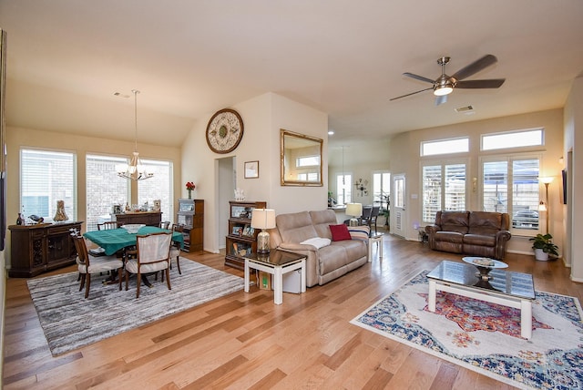 living room with ceiling fan with notable chandelier and light hardwood / wood-style floors