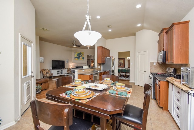 dining area featuring vaulted ceiling, sink, and light tile patterned floors